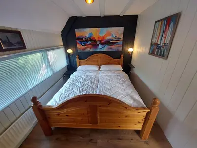 a bedroom with a wooden bed with a painting on the wall at Ferienhaus Holland in Opmeer