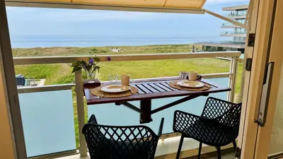 a table on a balcony with a view of the ocean at Strand Panorama Egmond in Egmond aan Zee