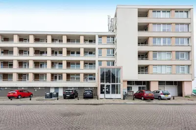 a large building with cars parked in front of it at Strand Panorama Egmond in Egmond aan Zee