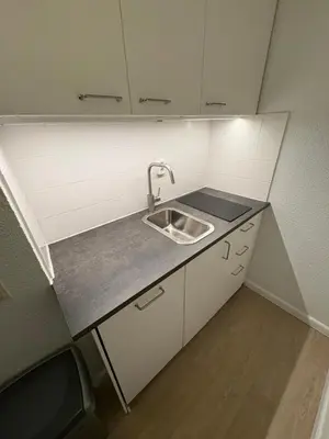 a small kitchen with a sink and white cabinets at Studio B in Egmond aan Zee