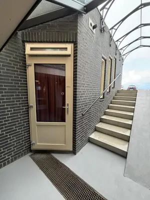 a door on a brick building with stairs at Studio B in Egmond aan Zee