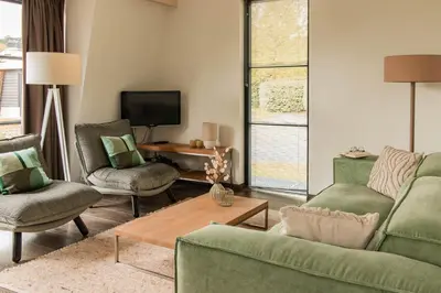 a living room with a couch and chairs and a tv at Dutchen Park Weideduyn in Schoorl