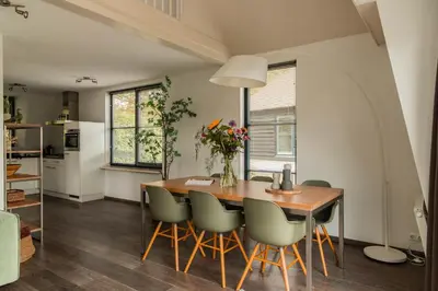 a kitchen and dining room with a wooden table and chairs at Dutchen Park Weideduyn in Schoorl