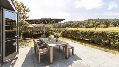 a wooden table and chairs with an umbrella on a patio at Dutchen Park Weideduyn in Schoorl