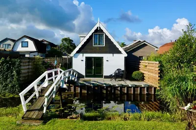 a house with a bridge over a body of water at B&B De groene loper in Sint Pancras