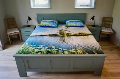 a bed with a painting of a man in the water at B&B De groene loper in Sint Pancras