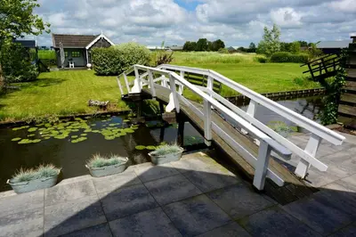 a white bridge over a pond with some plants at B&B De groene loper in Sint Pancras