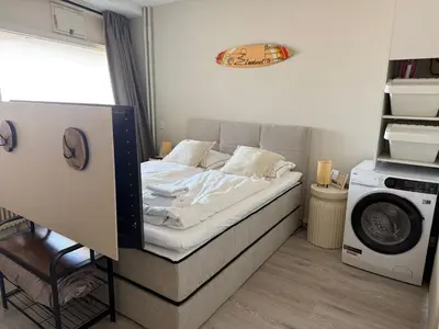 a small bedroom with a bed and a washing machine at Beach Loft in Zandvoort