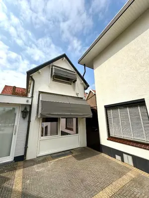 a white house with a window and an awning at Cosy Home Zandvoort in Zandvoort
