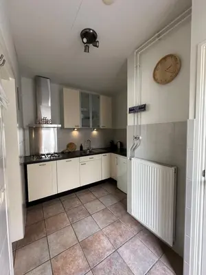 a kitchen with white cabinets and a clock on the wall at Cosy Home Zandvoort in Zandvoort