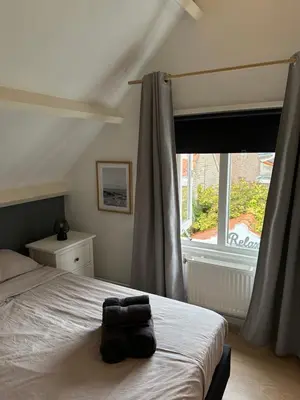 a bedroom with a bed and a large window at Cosy Home Zandvoort in Zandvoort