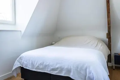 a white bed in a bedroom with a window at Central Art Apartment - Nieuwmarkt area in Amsterdam