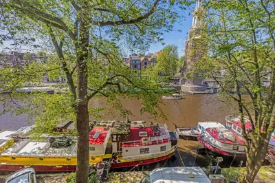 a group of boats are docked in a river at Central Art Apartment - Nieuwmarkt area in Amsterdam