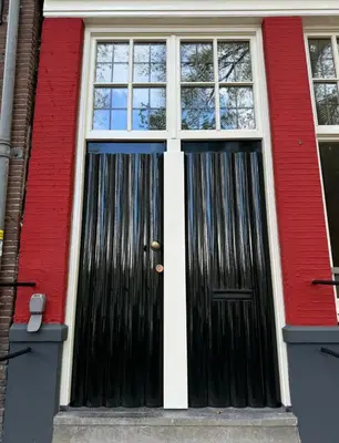 a black door on the side of a red building at Central Art Apartment - Nieuwmarkt area in Amsterdam