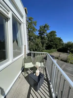 a balcony with two chairs and a vase on it at Burgervlotbrug aan zee met sauna in Burgerbrug