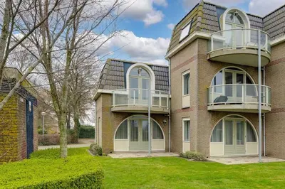 a large brick building with a balcony at Burgervlotbrug aan zee met sauna in Burgerbrug