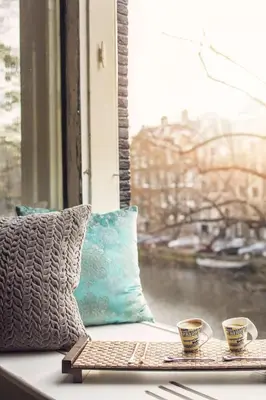 two cups on a window sill with a view of a river at KeizersgrachtSuite471 in Amsterdam