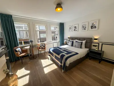 a bedroom with a bed and a table and windows at Yourbnb Suites Haarlemmerstraat in Amsterdam