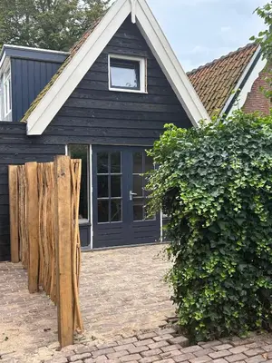 a black house with a window and a wooden fence at Westerhuysje in Uitgeest