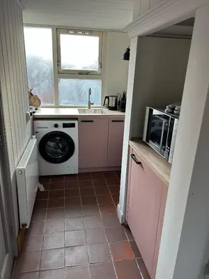 a small kitchen with a washing machine and a microwave at Westerhuysje in Uitgeest