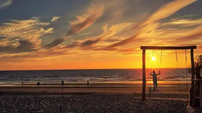 a person on a swing on the beach at sunset at Guesthouse Porter Noordwijk in Noordwijk