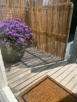 a wooden deck with a vase of purple flowers at Hartje Bergen in Bergen