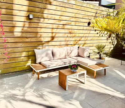 a couch sitting on a patio next to a wooden wall at Souterrain Sandy Sous in Noordwijk