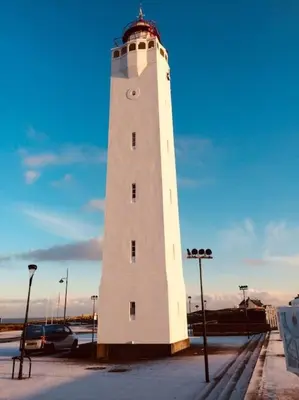 a white lighthouse with a clock on it in a parking lot at Souterrain Sandy Sous in Noordwijk