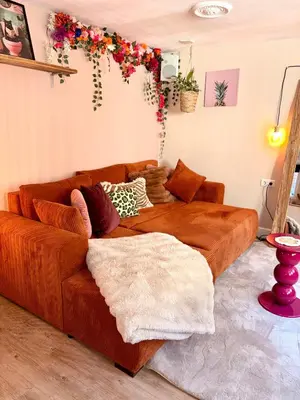 a brown couch in a living room with flowers on the wall at Souterrain Sandy Sous in Noordwijk
