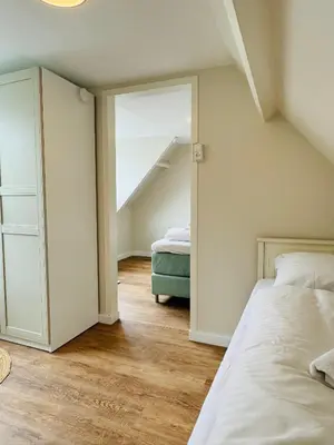an attic bedroom with two beds and a mirror at Ocean Breeze - Noordwijk aan Zee in Noordwijk aan Zee