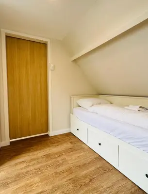 an attic bedroom with two beds and a closet at Ocean Breeze - Noordwijk aan Zee in Noordwijk aan Zee