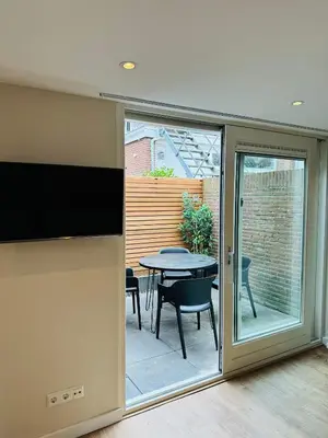 a sliding glass door leading to a patio with a table at Ocean Breeze - Noordwijk aan Zee in Noordwijk aan Zee