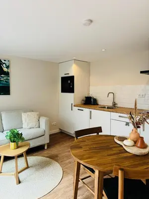 a living room with a table and a kitchen at Ocean Breeze - Noordwijk aan Zee in Noordwijk aan Zee