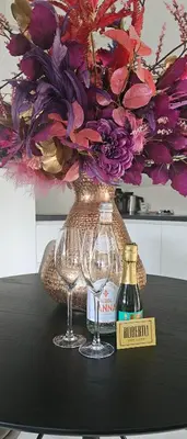 two wine glasses and a vase with a flower arrangement at Casa Roberto in Alkmaar