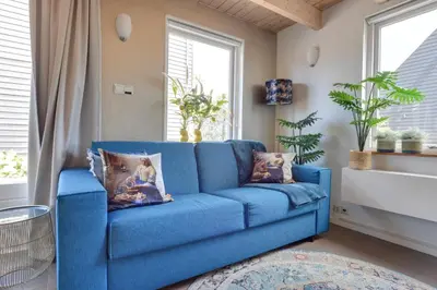 a blue couch in a living room with windows at 't Hutje centrum Uitgeest in Uitgeest