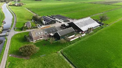 an aerial view of a farm with a building and grass at Hooiberghut op boerderij in Leidschendam