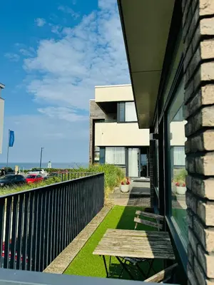 a balcony of a house with a wooden bench at Beachhouse Seepaertje - Boulevard Noordwijk aan Zee in Noordwijk aan Zee