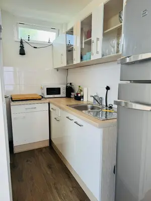 a kitchen with white cabinets and a sink at Beachhouse Seepaertje - Boulevard Noordwijk aan Zee in Noordwijk aan Zee