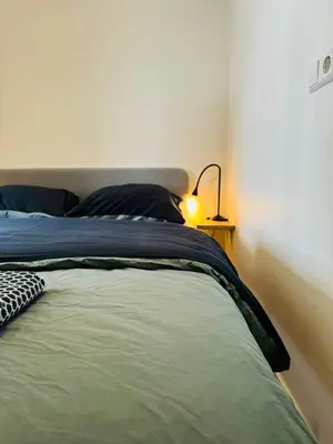 a bedroom with a bed with a blue blanket and a lamp at Beachhouse Seepaertje - Boulevard Noordwijk aan Zee in Noordwijk aan Zee