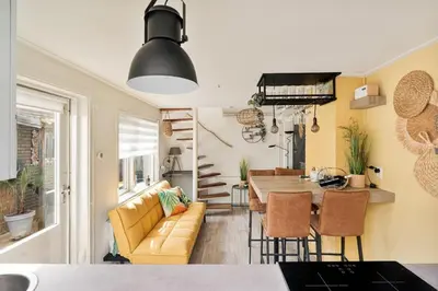 a kitchen and living room with a couch and a table at Hello Noordwijk - Quarles 43 in Noordwijk aan Zee