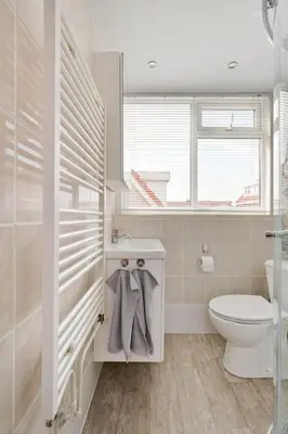 a white bathroom with a toilet and a window at Hello Noordwijk - Quarles 43 in Noordwijk aan Zee