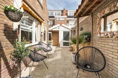 a patio with chairs and plants and a building at Hello Noordwijk - Quarles 43 in Noordwijk aan Zee