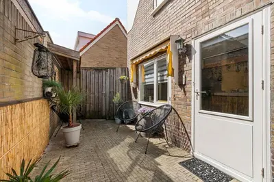 a patio with two chairs and a door at Hello Noordwijk - Quarles 43 in Noordwijk aan Zee