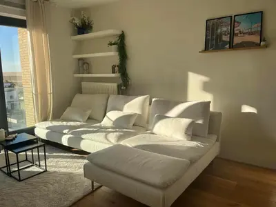 a living room with two white couches in front of a window at A few steps away apartment in Zandvoort