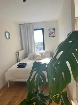 a bedroom with a bed with a plant in the foreground at A few steps away apartment in Zandvoort