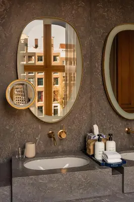 a bathroom with two mirrors and a sink at Rosewood Amsterdam in Amsterdam
