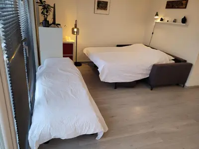 two beds in a room with white sheets at Bright room with kitchen in Amsterdam