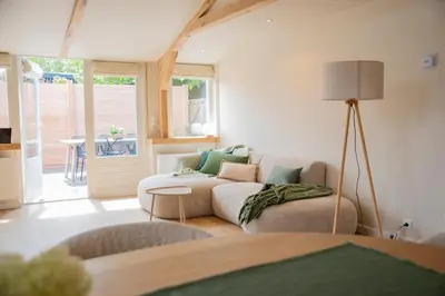 a living room with a couch and a lamp at Westeindercabin, rustige locatie maar naast Amsterdam & Schiphol in Aalsmeer