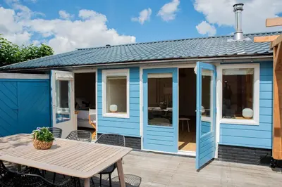 a blue shed with a wooden table and a picnic table at Westeindercabin, rustige locatie maar naast Amsterdam & Schiphol in Aalsmeer