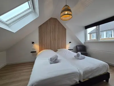 a bedroom with a large white bed with towels on it at Beach 44 in Egmond aan Zee